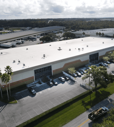 Aerial view of The Royal Group's co-packing and fulfillment facility, showcasing large warehouse structure, ample parking, and surrounding landscape, emphasizing extensive operational capacity and logistics capabilities.