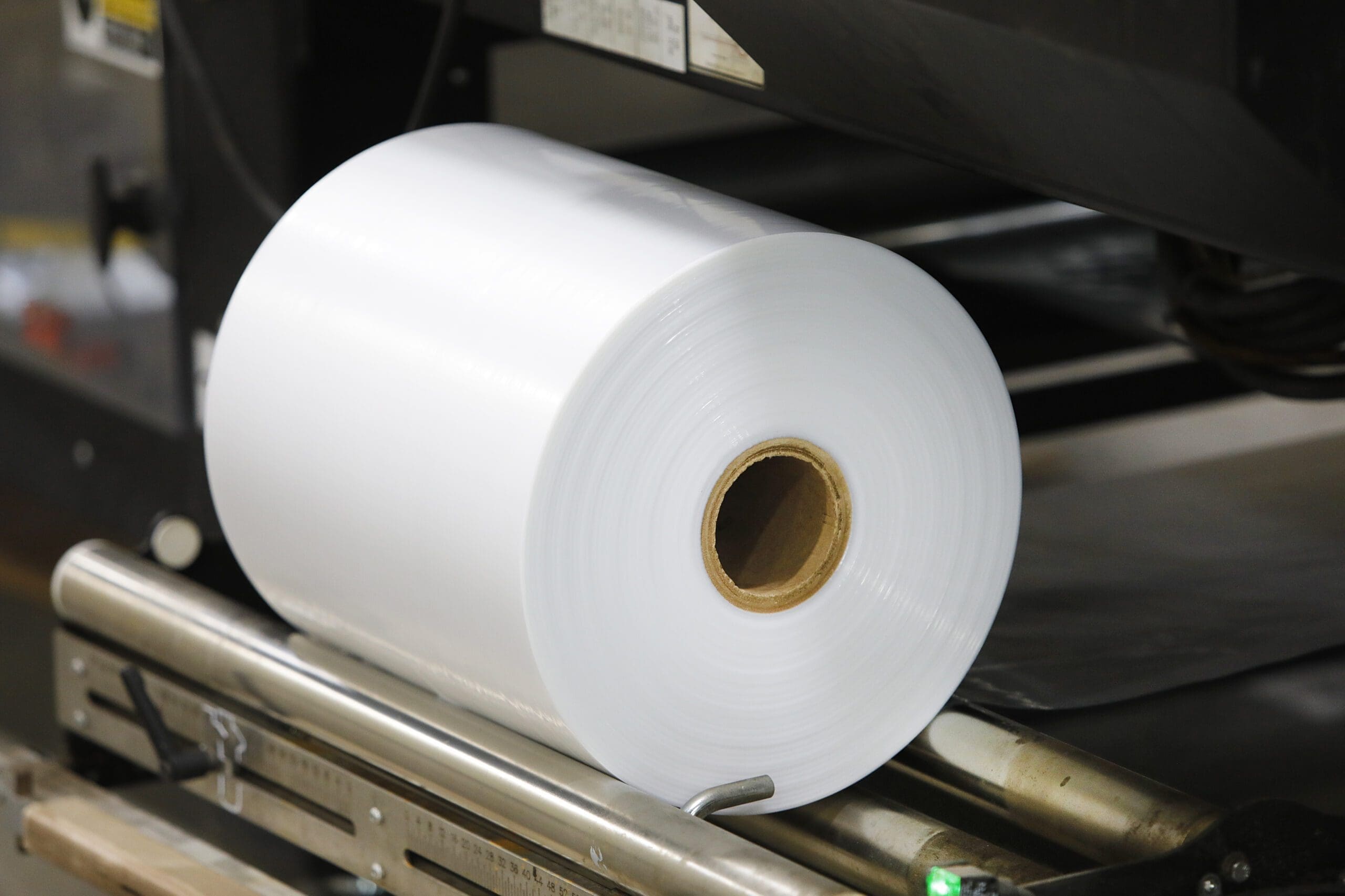 Roll of clear shrink wrap on machinery, highlighting packaging solutions for co-packing and fulfillment services at The Royal Group.