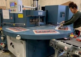 Worker operating shrink wrap machine in fulfillment facility, demonstrating TRG's co-packing services and packaging efficiency.
