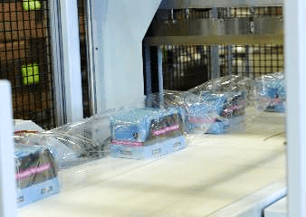 Shrink-wrapped products on a conveyor belt in a co-packing facility, illustrating The Royal Group's packaging and fulfillment services.