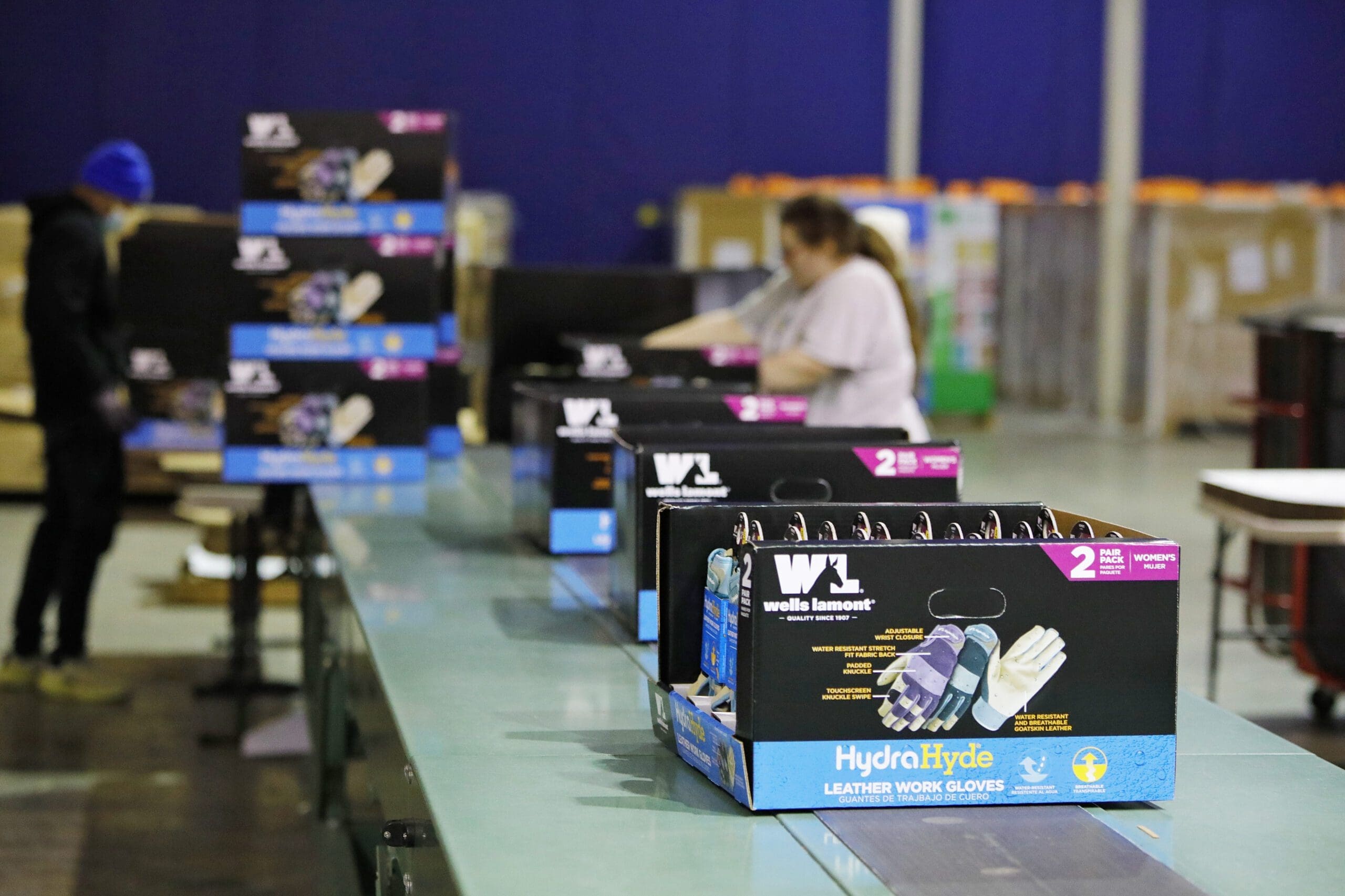 Workers assembling packaging for Wells Lamont HydraHyde leather work gloves in a fulfillment center, highlighting assembly and packaging solutions.
